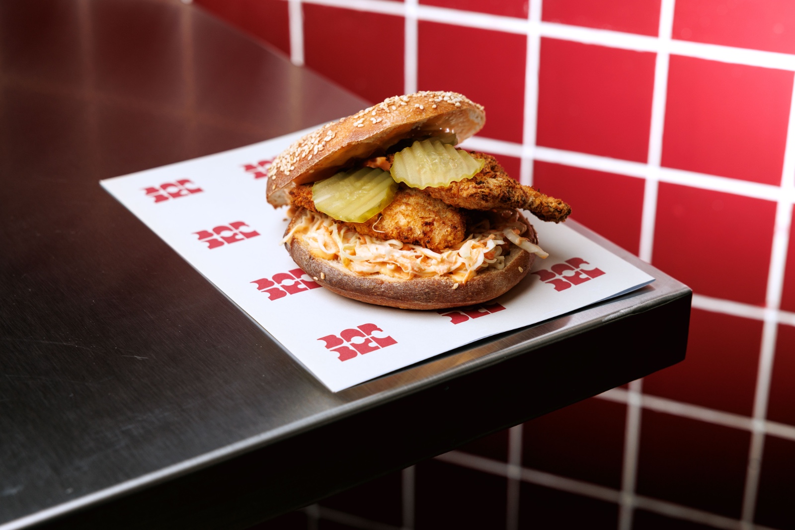 Crispy Chicken Bagel Burger — air fried chicken breast, cabbage carrot slaw, light siracha mayo, pickles.