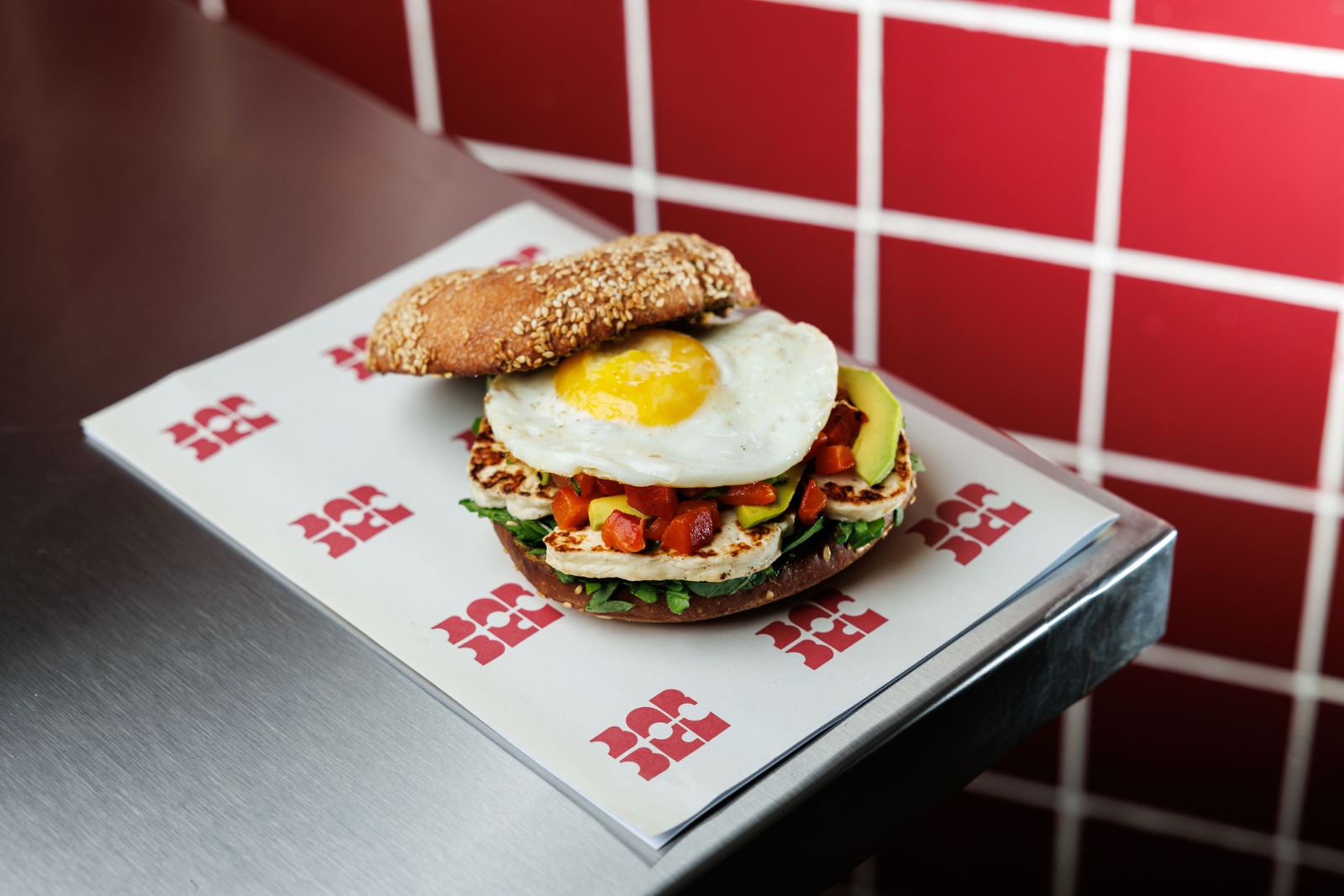 Halloumi Sunrise Bagel — hemp seeds basil pesto spread, arugula, grilled halloumi, avocado
slices, fried egg, roasted red pepper, sour dough ses...
